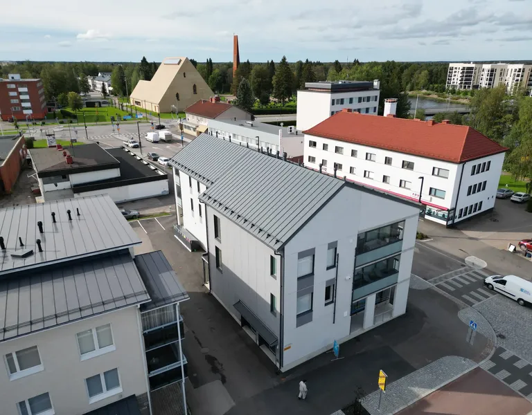 As Oy Sypin Kulman tummanharmaa konesaumakatto ilmasta, taustalla kirkko