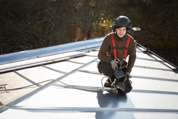 Vaskiseppien peltiseppä asentamassa uutta konesaumattua peltikattoa. Kattoremontti.