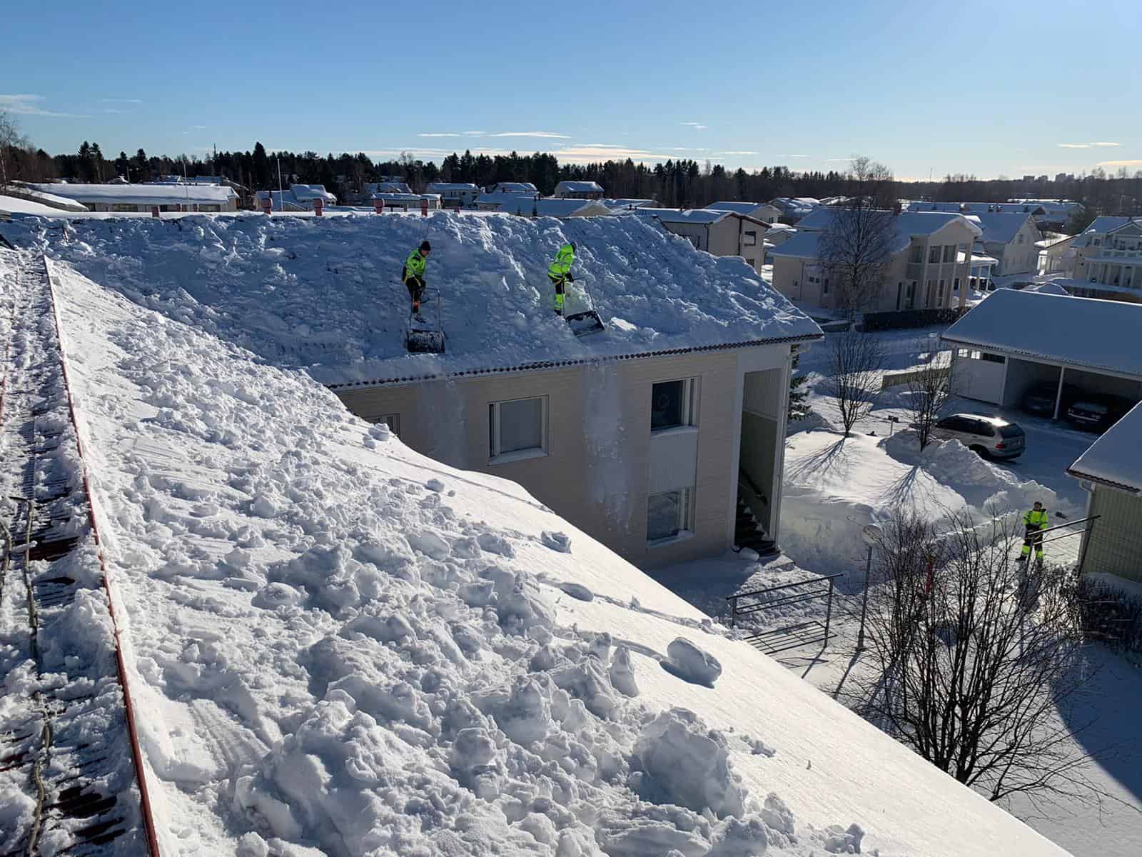Vaskiseppien kattoalan ammattilaiset pudottamassa lunta katolta